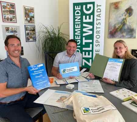 Bild von drei Personen an einem Tisch mit Urkunden und Zertifikaten