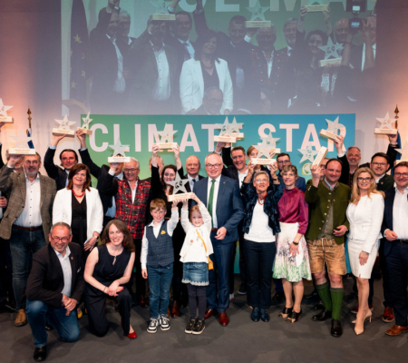 Personen auf einer Bühne mit den Climate Star Pokalen in der Hand.