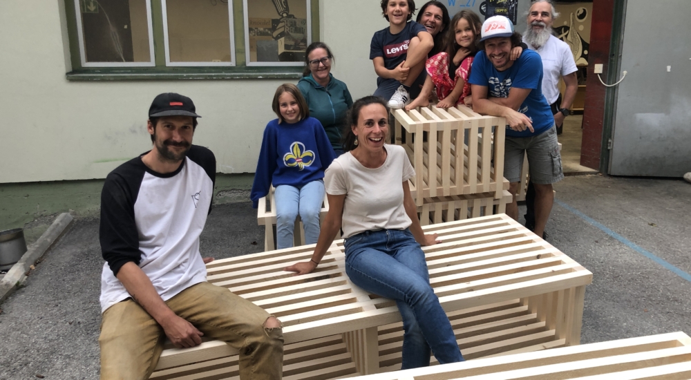 Personen sitzen auf selbstgebauten Bänken und lachen