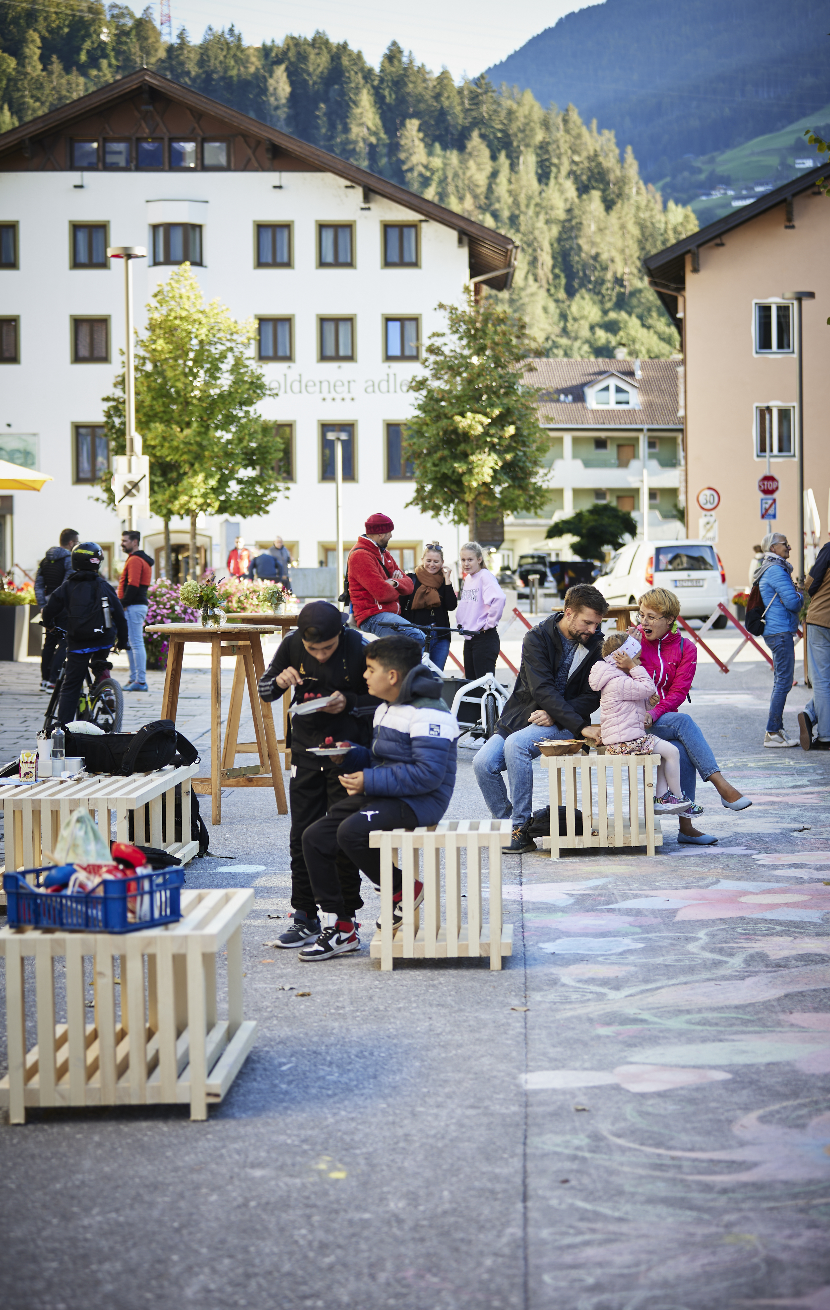 Personen auf Holzbänken auf der Straße in Wattens