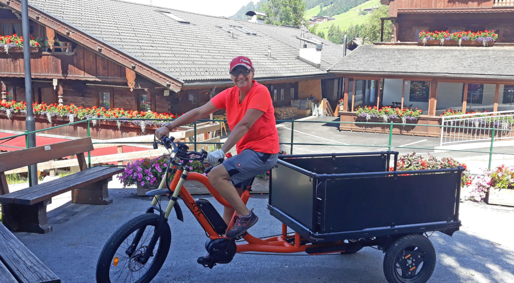 Frau in organgenem Shirt fährt ein Lastenfahrrad