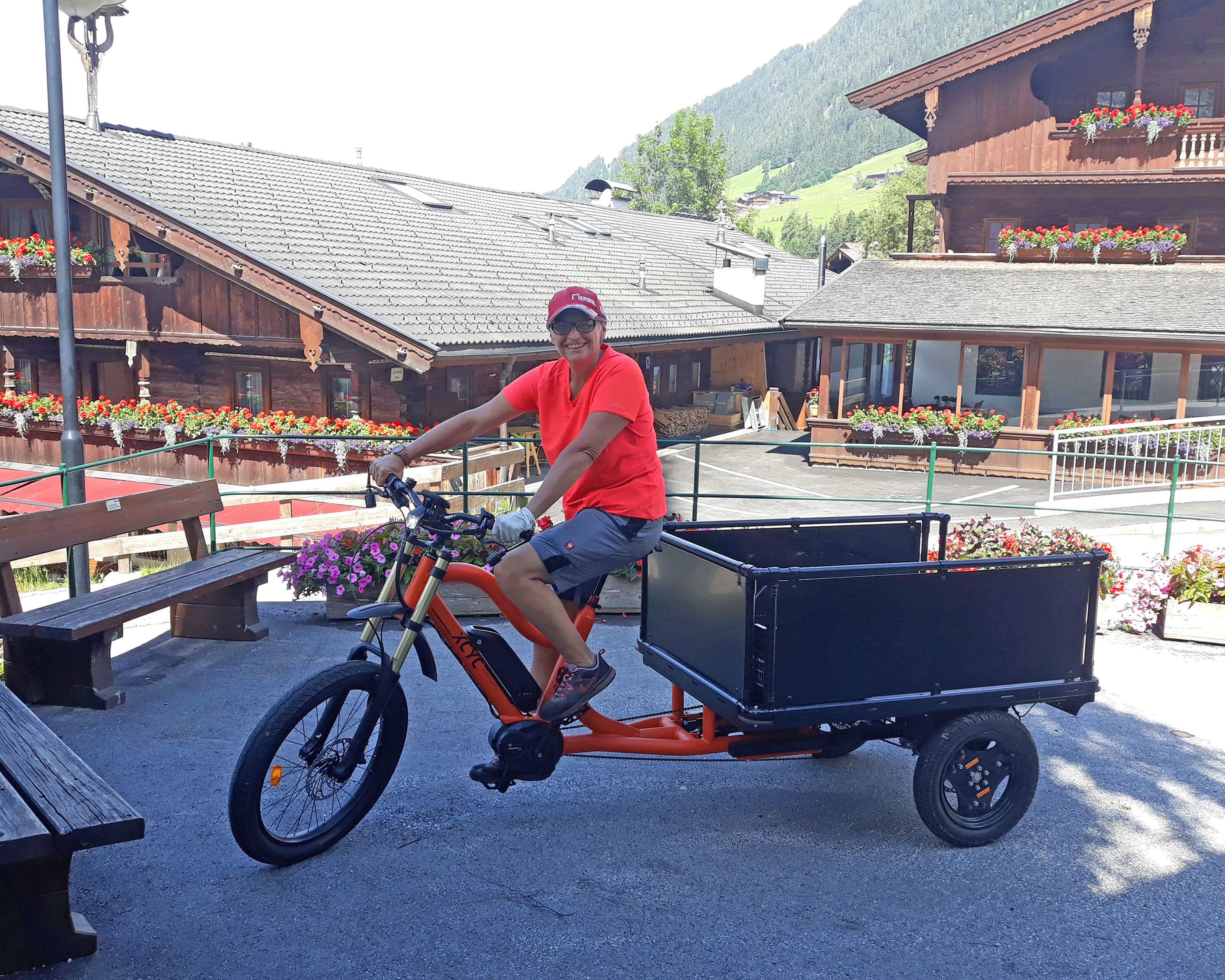 Frau in organgenem Shirt fährt ein Lastenfahrrad
