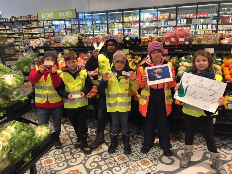 Kinder in Warnweste im Supermarkt machen darauf aufmerksam, dass wenig Plastik verwendet werden soll