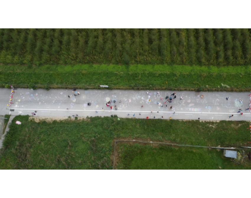 Ansicht einer Straße aus der Vogelperspektive – mit Zeichnungen von Kindern und Personen, die sich auf der Straße aufhalten. Es sind keine Autos zu sehen.