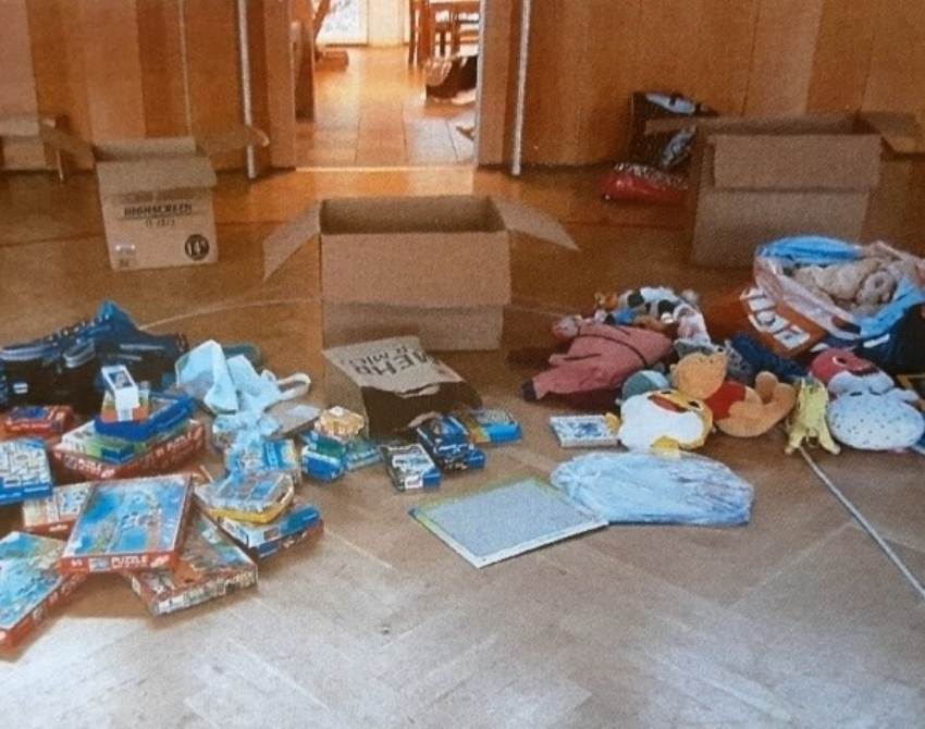 Schachteln, Spiele und Bücher liegen auf dem Holzboden
