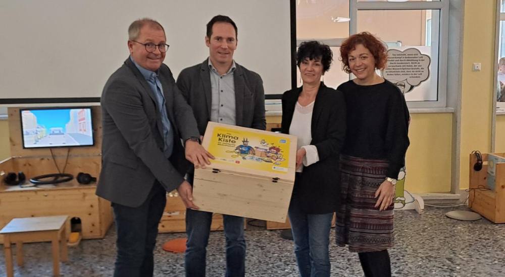 Gruppenbild von Bernd Osprian – Bürgerrmeister von Voitsberg, Fritz Hofer – Geschäftsführer Klimabündnis Steiermark, Claudia Nestler – Stadtbücherei Voitsberg, Cornelia Schweiner – Bildungsreferentin des Landes Steiermark (Abt. 15) in der Mitte tragen sie die Klimakiste