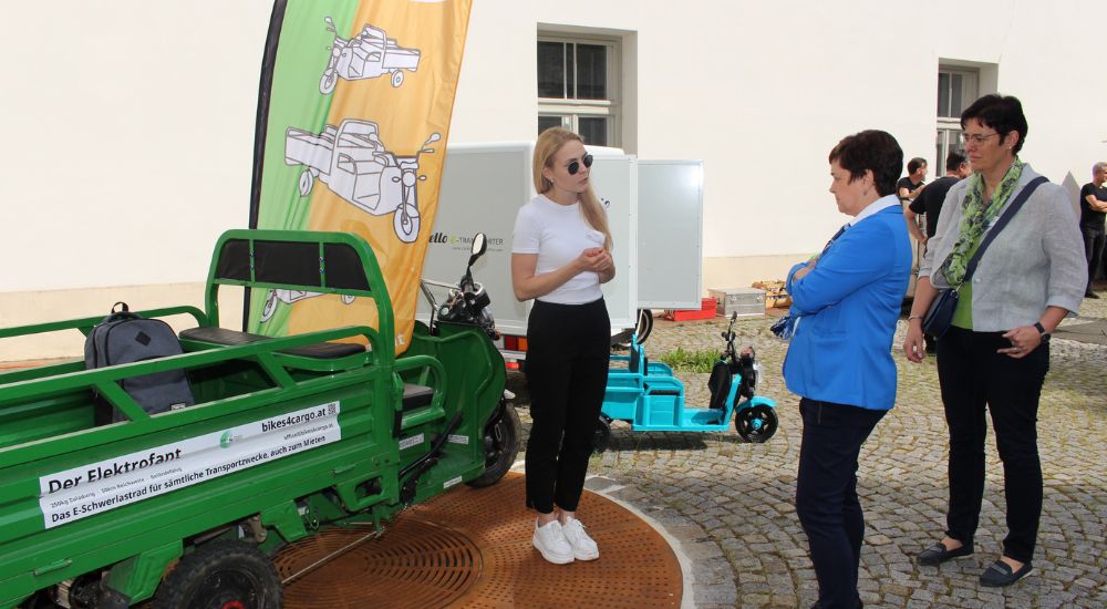 Tuktuk, davor steht eine Frau und unterhält sich mit zwei anderen Frauen