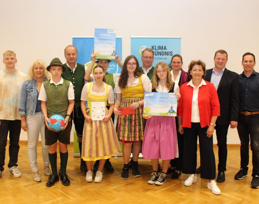 Gruppenbild von Kindern mit Urkunden, einem großen Scheck und Gutscheinen in der Hand, und einem Fußball, mit Erwachsenen am Bildrand, dahinter zwei Roll-Ups