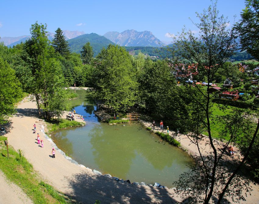Blick von oben auf Teich, mit Schotterweg rund herum und Bäumen