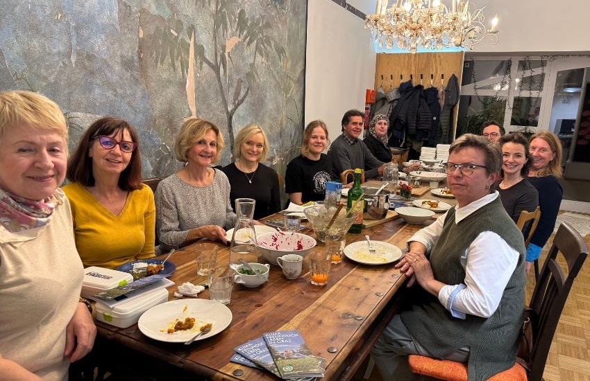 Gruppenbild. Menschen sitzen an langer Tafel