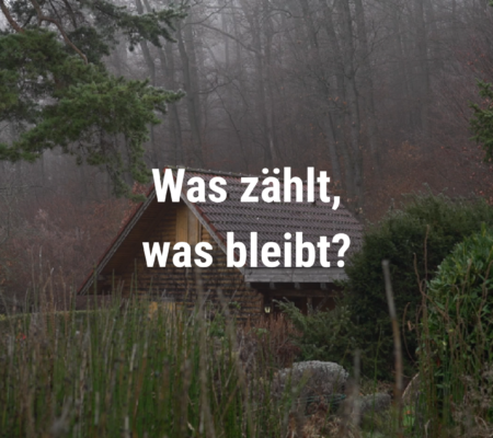 Was zählt was bleibt - Schrift vor Hintergrund aus Holzhütte im Wald