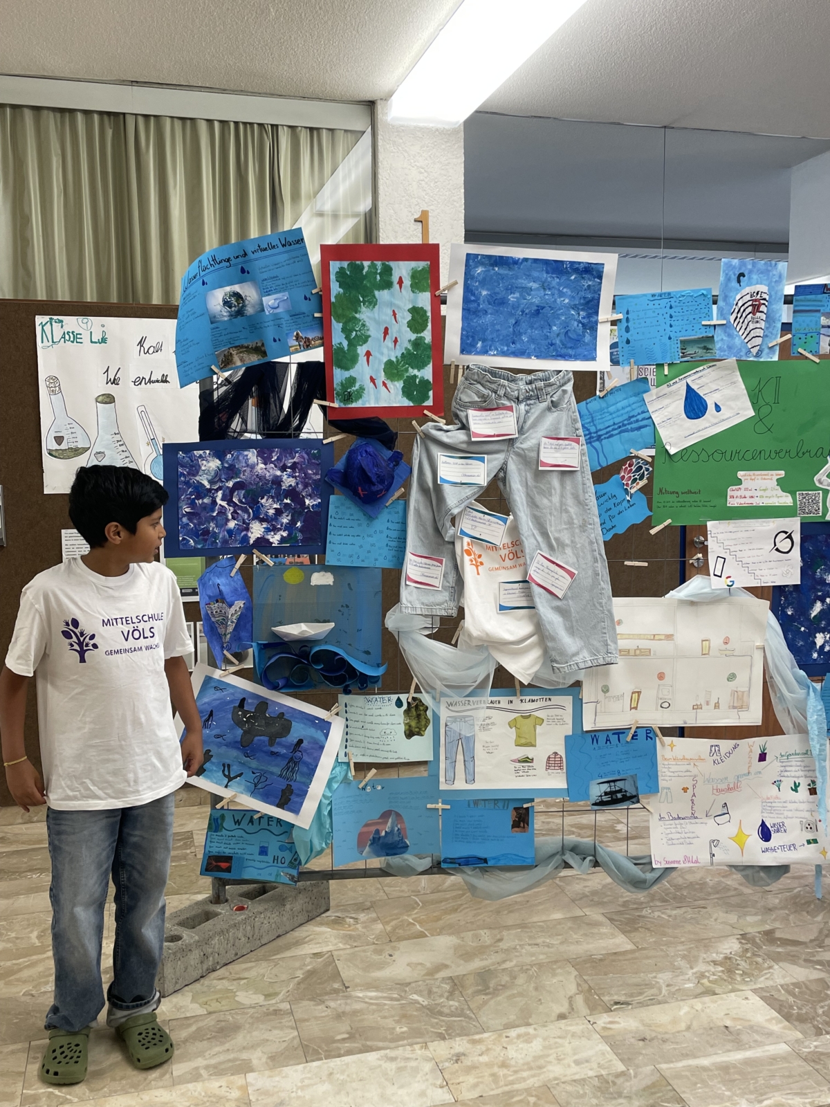 Schüler vor einer Sammlung von Texten und Bildern zum Thema Wasser